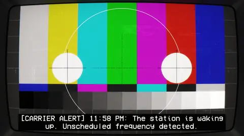 A television test card of colour bars at 11:58 PM, with a carrier alert caption.
